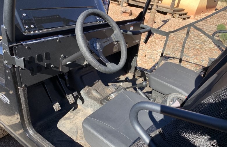Mahindra Roxor operator station with stick shift manual transmission, basic steering wheel, and two seats
